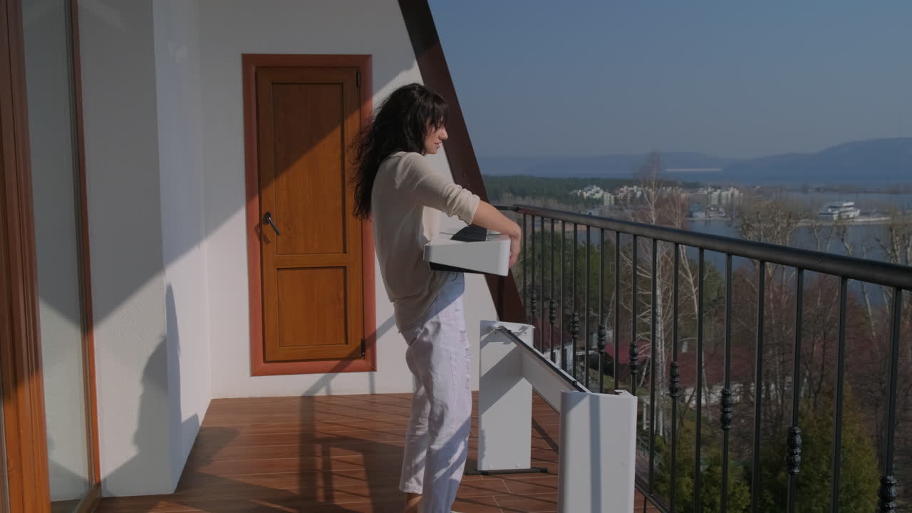 Woman Playing Piano on a Balcony with Lake View