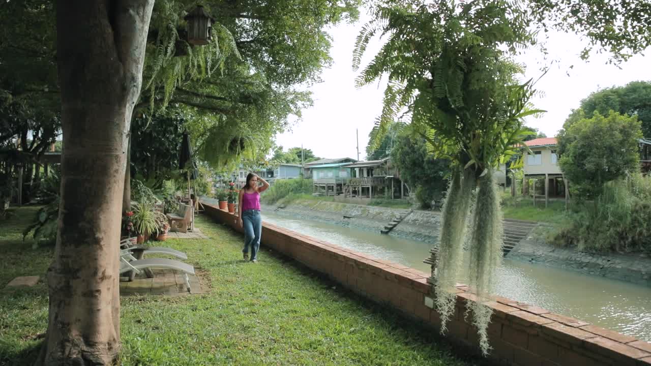 Thai Lady Walking in a Peaceful Garden Next to a Canal in Ayutthaya, Thailand