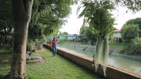 thai lady walking in a peaceful garden next to a canal in ayutthaya, thailand