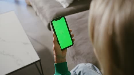 woman holding a phone with a green screen