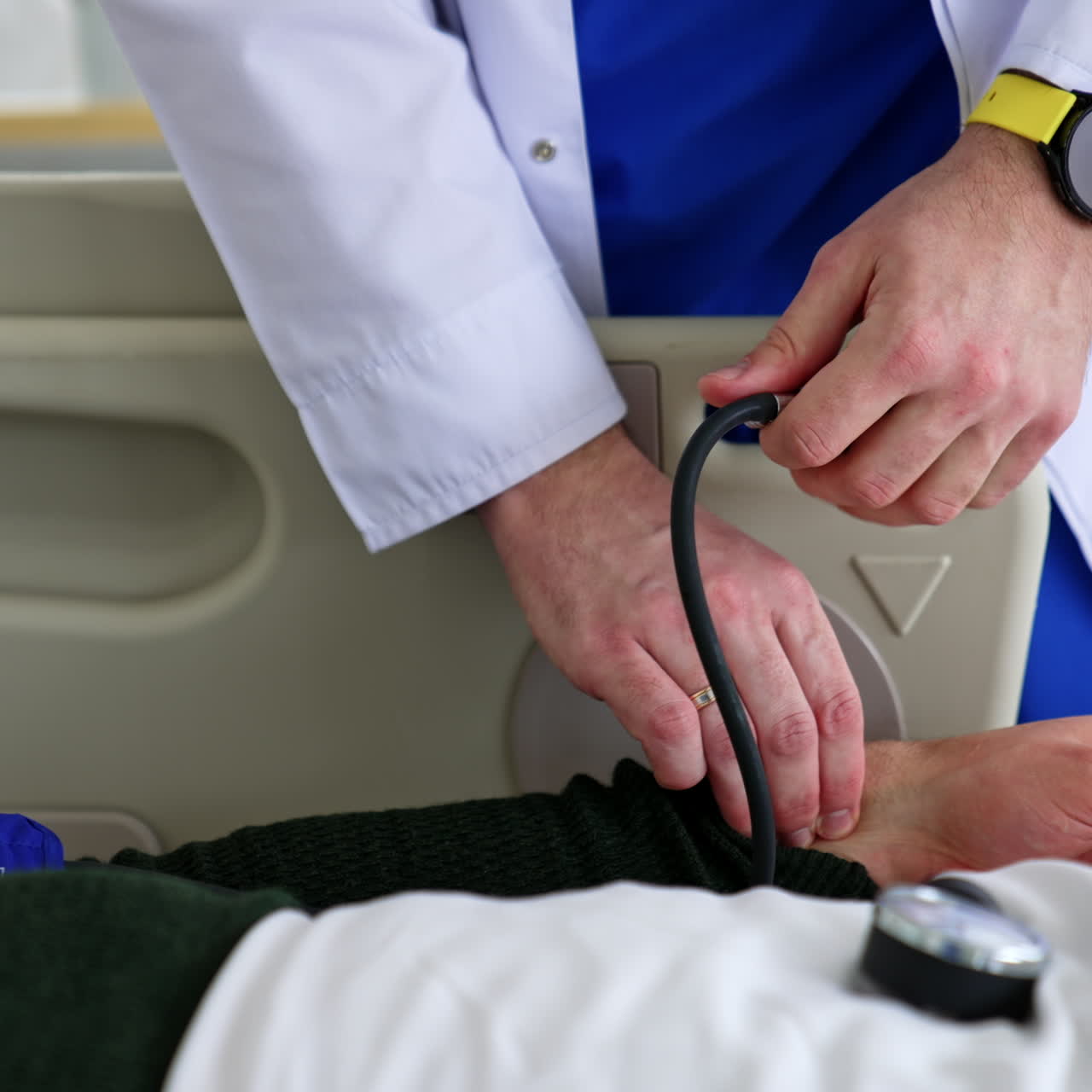 Hands of male doctor measuring blood pressure of a patient lying on the bed. Taking care of an ill person