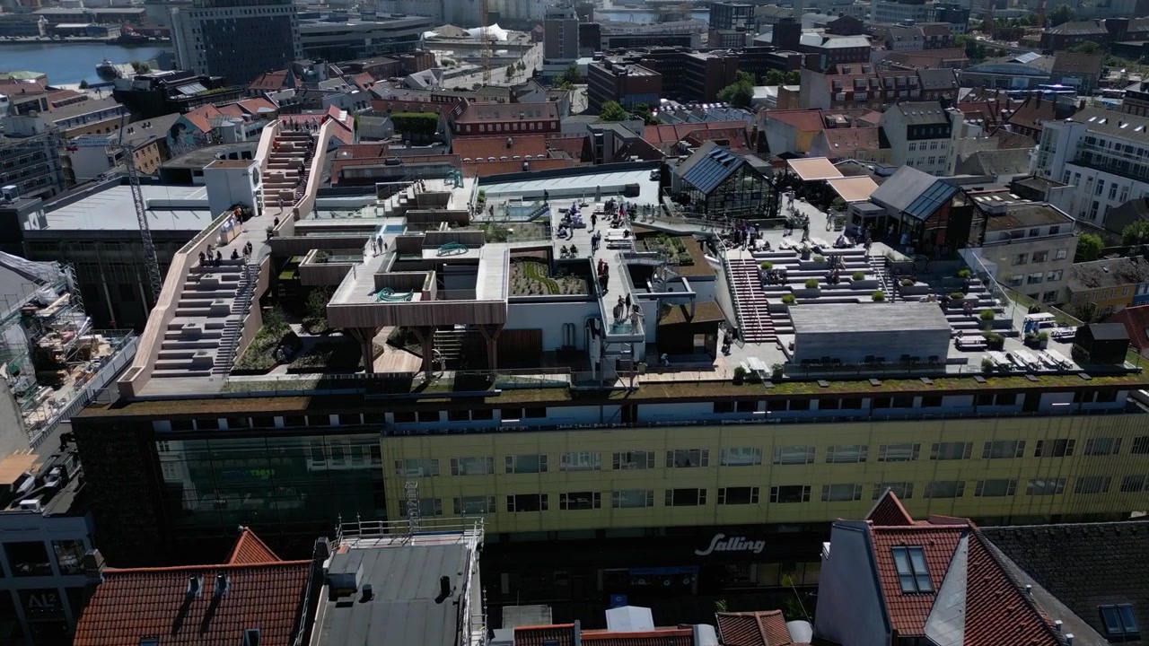 Salling Rooftop terraces above central Aarhus with surrounding city buildings, Denmark, aerial ascend above visitors walking and roaming around