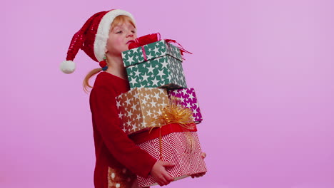niña con suéter de navidad, sombrero de papá noel, sonriendo, sosteniendo muchas cajas de regalos compras de regalos de año nuevo