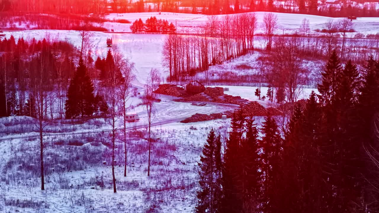 Un paesaggio invernale con foreste e strade assume un bagliore rosso sotto un tramonto.
