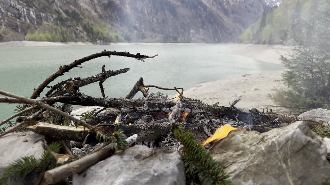A fire of firewood for cooking in an adventure activity on the shores of the lake Kl&ouml;ntalersee Glarus Kanton in Switzerland