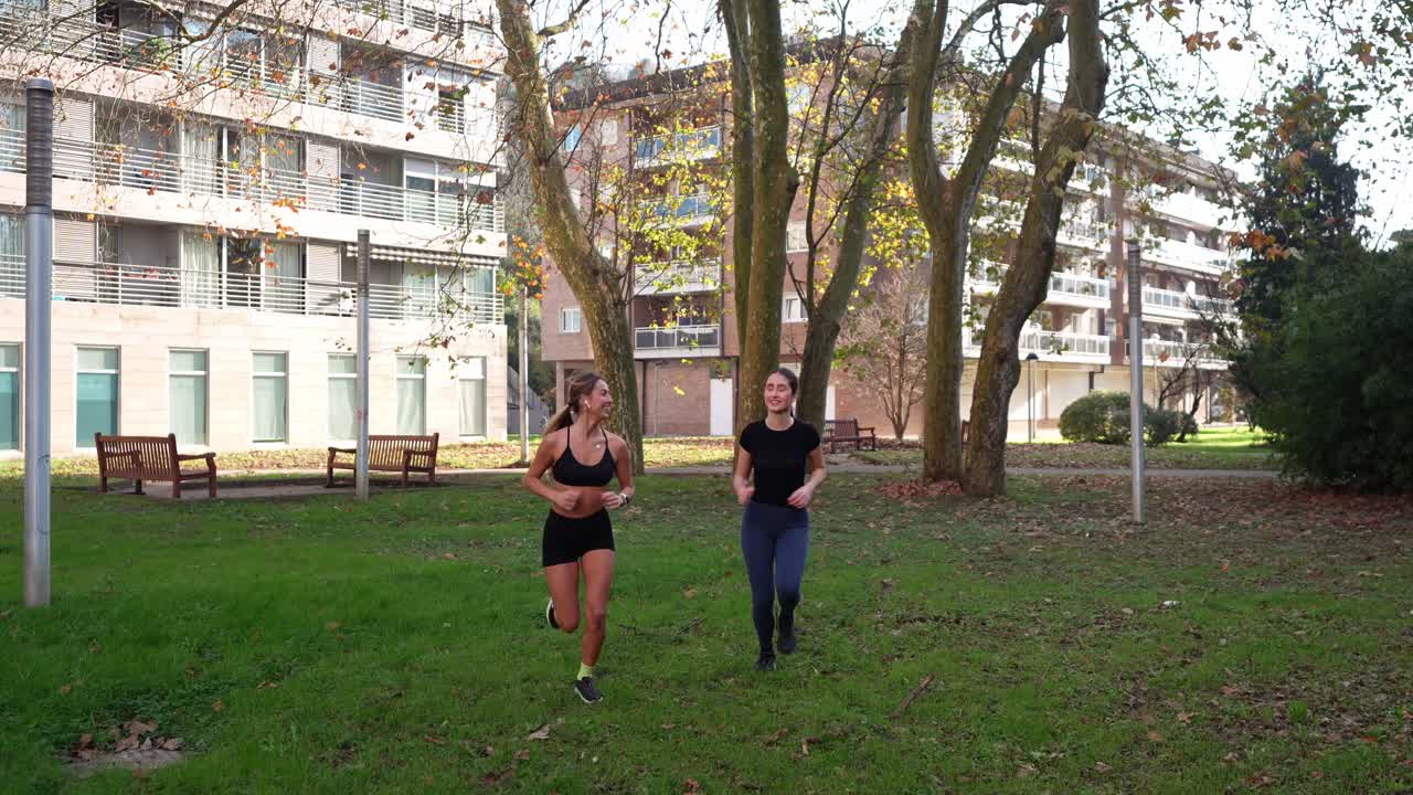 To kvinder, der jogger i en park, giver hinanden en high five