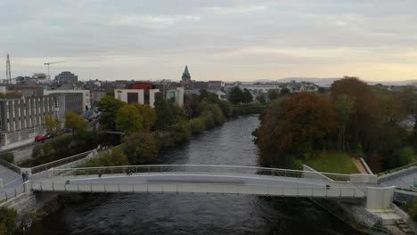 Zeitlupenaufnahme-Des-Sanften-Flusses-Und-Der-Fußgänger,-Die-Die-Lachswehrbrücke-In-Galway-überqueren