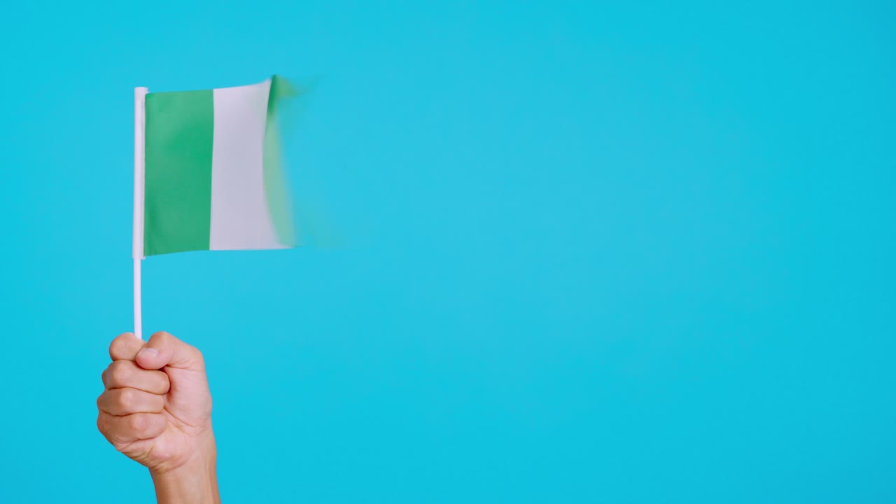 Wind waving a nigerian pennant holding by a hand