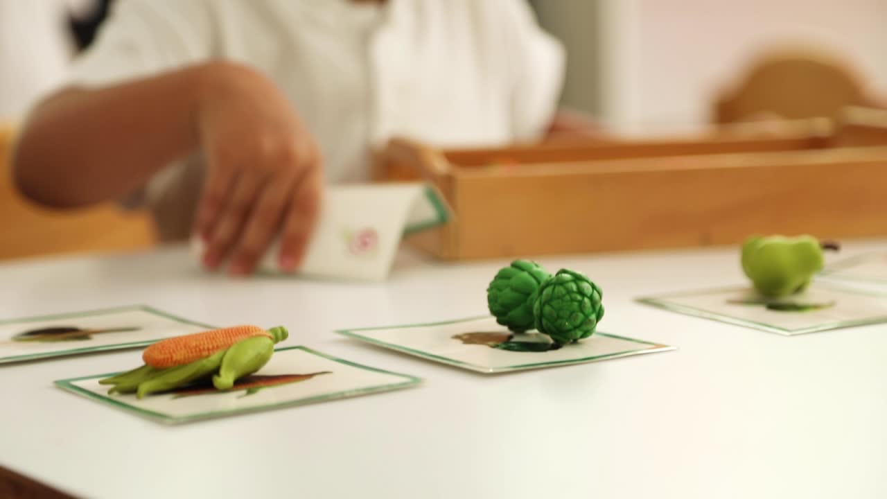 Child playing in a Montessori class with food themed objects and cards