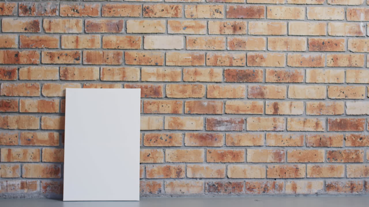 Video of white canvas sign with copy space on floor against brick wall background
