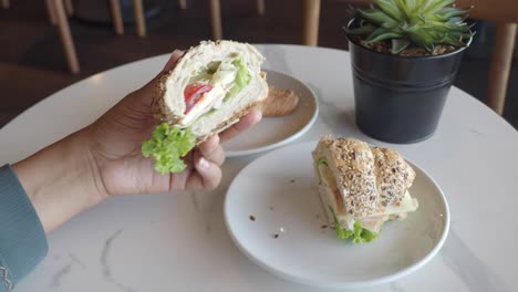 カフェでサンドイッチとクロワッサンを握っている人