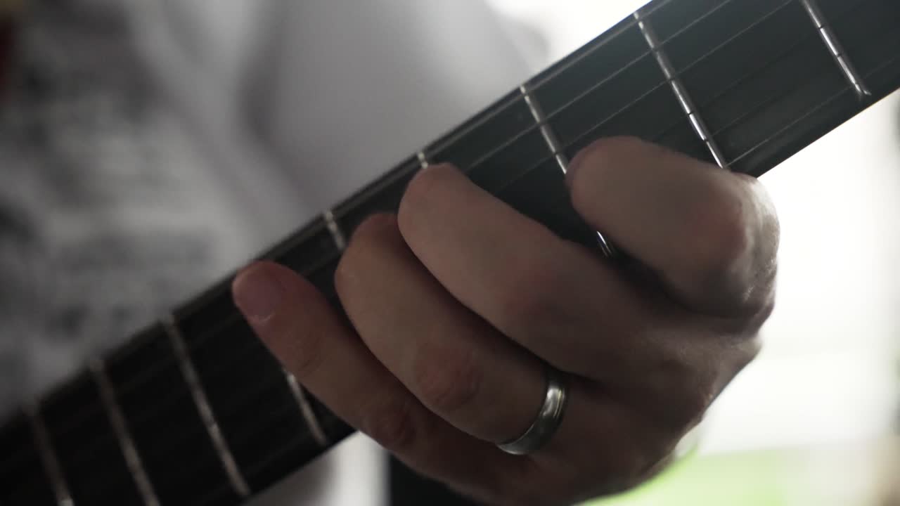 primer plano de la mano del músico tocando solo la guitarra eléctrica en cámara lenta, hombre, camisa blanca