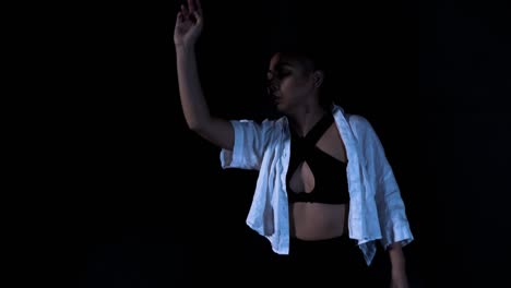 hermosa joven bailando golpeando en liberación sensual en fondo negro dramático