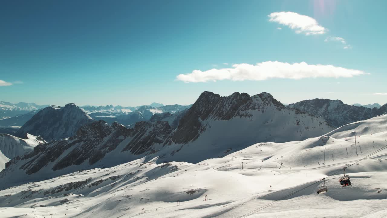 Arka planda kış sporlarına katılan insanlar varken telesiyejlerin drone çekimi - Zugspitze, Bavyera, Almanya