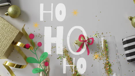 ho text animation over christmas decorations with gifts and ornaments
