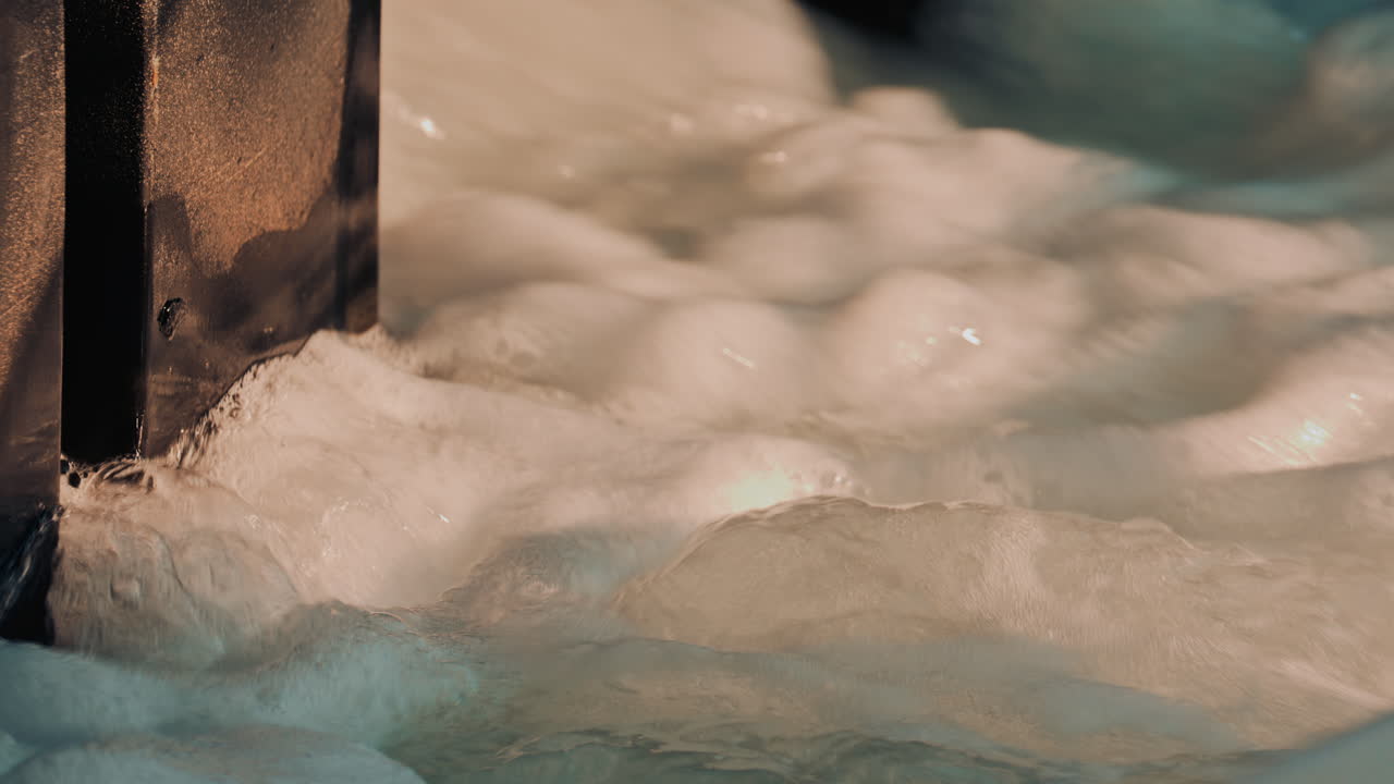 Close up shot of contaminated seawater with clusters of foam and oily bubbles drifting across the surface