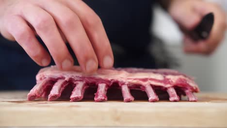 chef begins trimming fat on rack of lamb