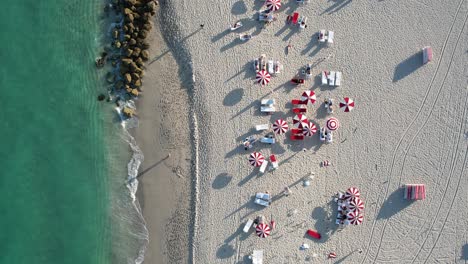 aerial view rising above sun beds and parasols at miami beach, in florida, usa - birds eye, drone shot