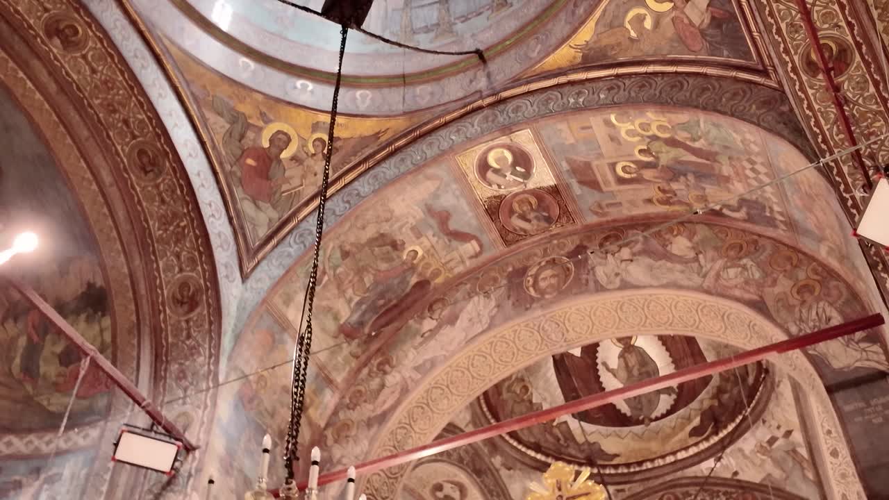 Vista interna della Cattedrale Patriarcale di Bucarest, con panoramica dall'alto verso il basso, dagli affreschi decorati del soffitto e dal lampadario all'altare dorato