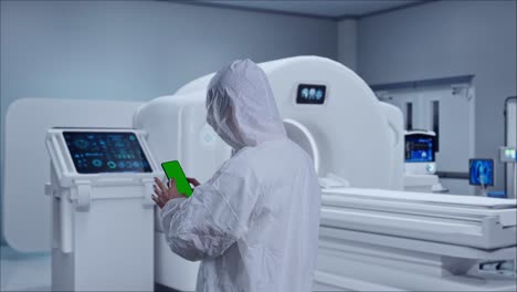 back view of asian male scientist use mock up green screen smartphone while standing with mri machine in the hospital