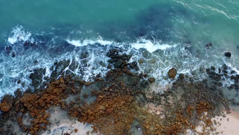 Wunderschöner-Blick-Aus-Der-Vogelperspektive-Auf-Meereswellen,-Die-An-Einem-Warmen-Sommertag-Am-Ufer-Eines-Tropischen-Strandes-Im-Norden-Brasiliens-Namens-Tabatinga-Mit-Blauem-Wasser-Und-Goldenem-Sand-In-Der-Nähe-Von-Joao-Pessoa-Auf-Felsen-Treffen