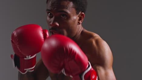 Close-Up-Studio-Shot-Of-Tattooed-Male-Boxer-Wearing-Boxing-Gloves-In-Boxing-Match-Throwing-Punches