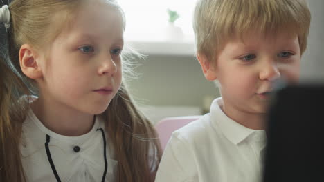 toddler boy talks to sister looking at laptop monitor