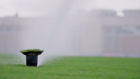 Static-slow-motion-shot-of-a-sprinkler-watering-a-soccer-field