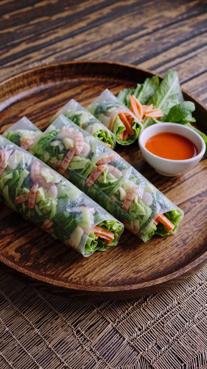 Lumpia segar dengan udang dan sayuran di atas piring kayu