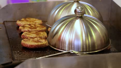 la carne de res se cocina en una sartén caliente. comida callejera, el chef lanza hamburguesas con una espátula.