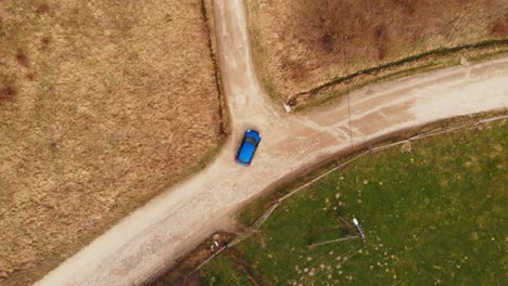 Ein-Blaues-Auto-Fährt-Von-Einer-Schmalen-Landstraße-Zurück-Und-Fährt-Dann-Auf-Einer-Anderen-Weiter