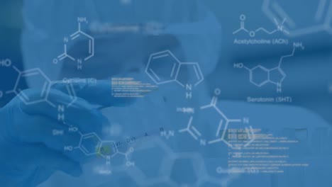 Scientist-in-protective-clothes-in-laboratory-with-data-and-structural-formula-of-chemical-compounds