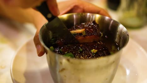 chef cortando carne de cerdo asada en un recipiente de metal