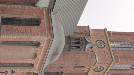 disparo vertical de una mujer caminando fuera de la iglesia de riddarholmen con una torre de ladrillo y una aguja de hierro fundido en el fondo