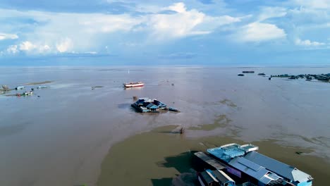 aerial fly over shot at the start of monsoon season, a floating village on the shores of the tonle sap lake, cambodia