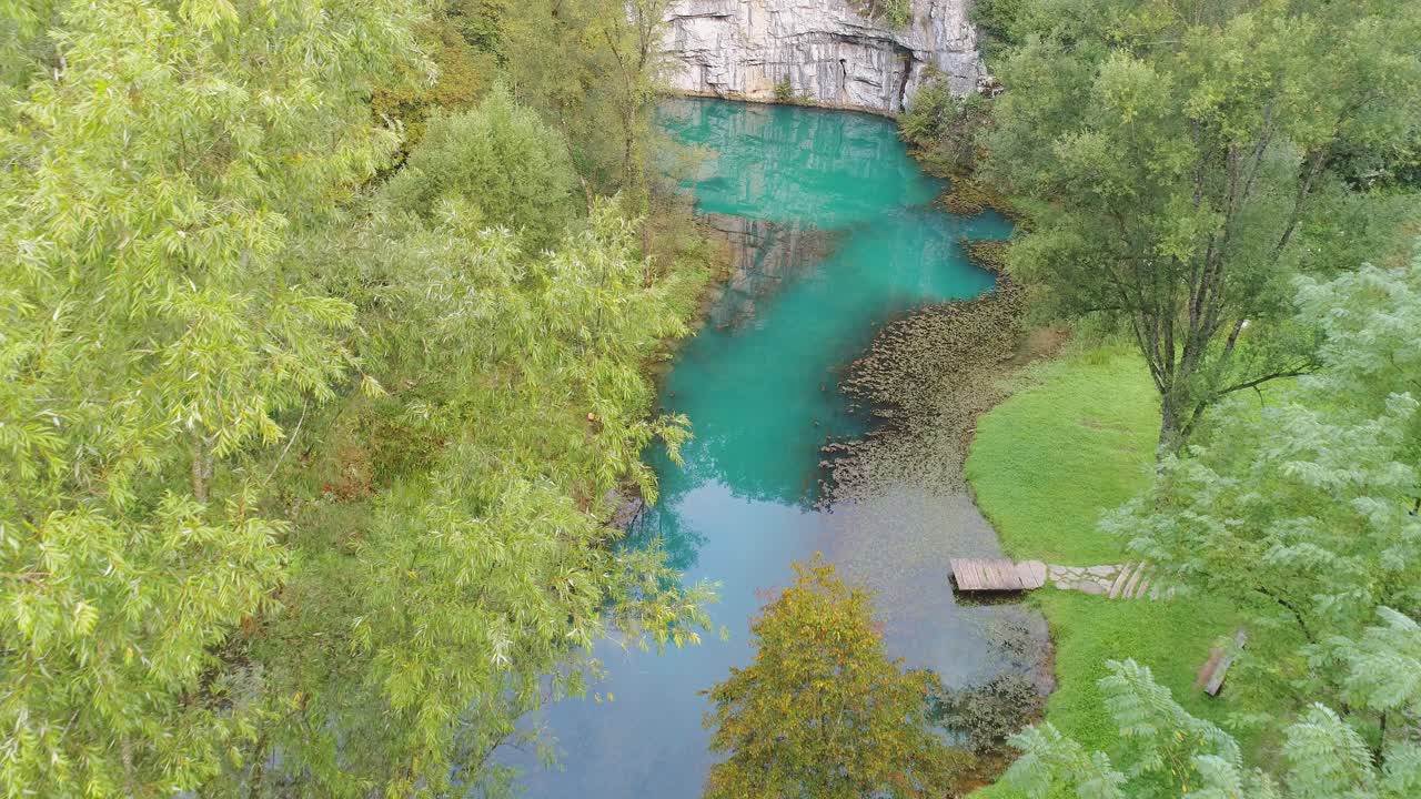 Aerial view of blue waters of Krupa river under rock wall amidst dense greenery in Semic, Slovenia