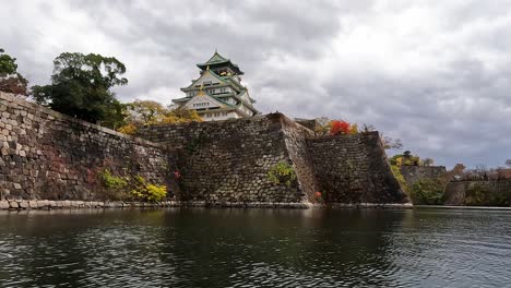 main building of osaka castle with green trees around castle in autumn, osaka