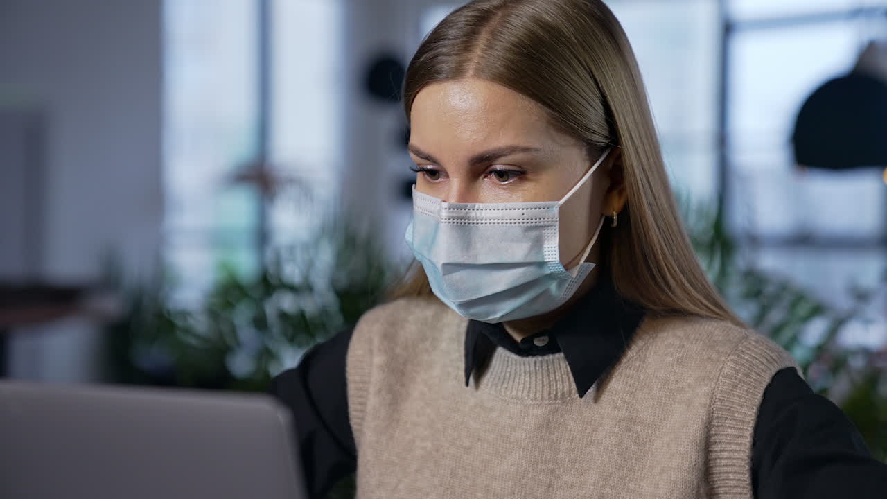Pretty young lady in mask working with computer. Portrait quarantine employee in mask.
