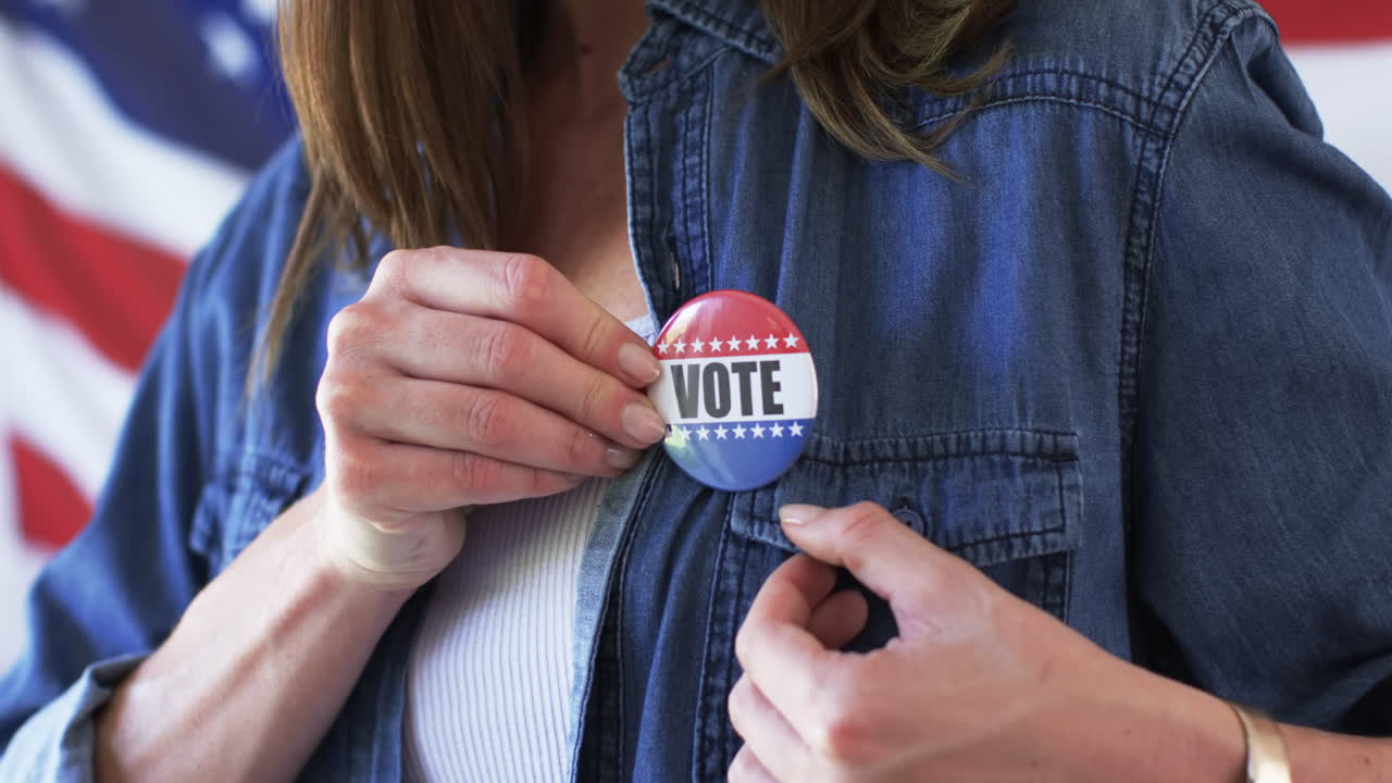 Middle-aged Caucasian woman pins a 'VOTE' badge on her shirt, with copy space