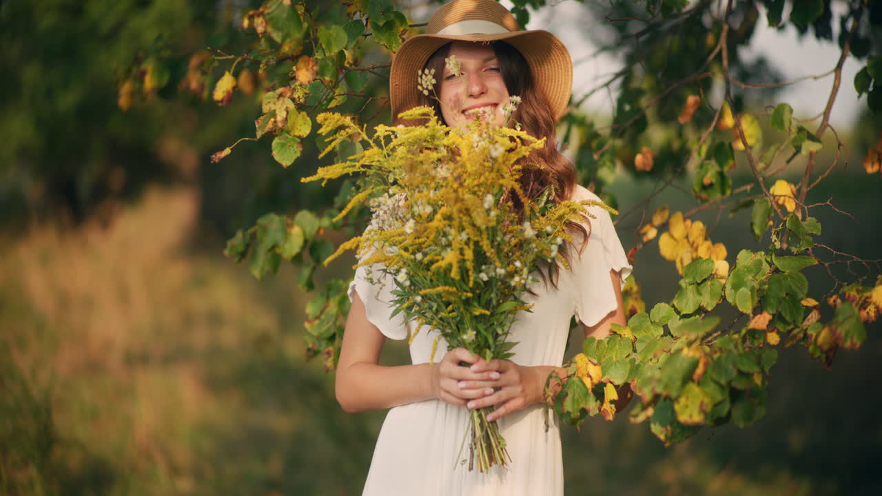 Dreamy girl in hat holding wildflowers bouquet
