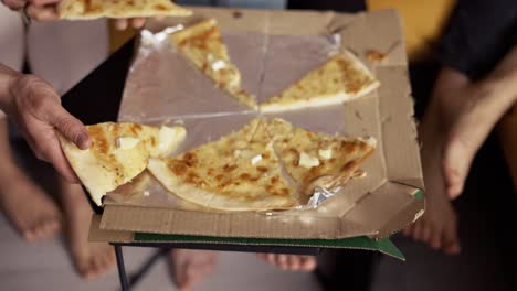 Male-and-female-hands-taking-slices-of-pizza-from-food-delivery