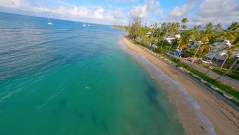 FPV-drone-flight-along-tropical-sandy-coastline-of-Playa-Las-Terrenas,-Caribbean