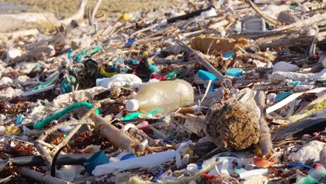 Inclinación-De-Cerca-De-Desechos-De-Basura-De-Plástico-Esparcidos-En-Una-Playa-Rocosa-En-El-Caribe