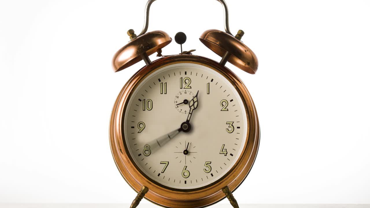CLock hand spinning fast time lapse. Clock hand spinning fast on vintage bronze alarm-clock on white background.