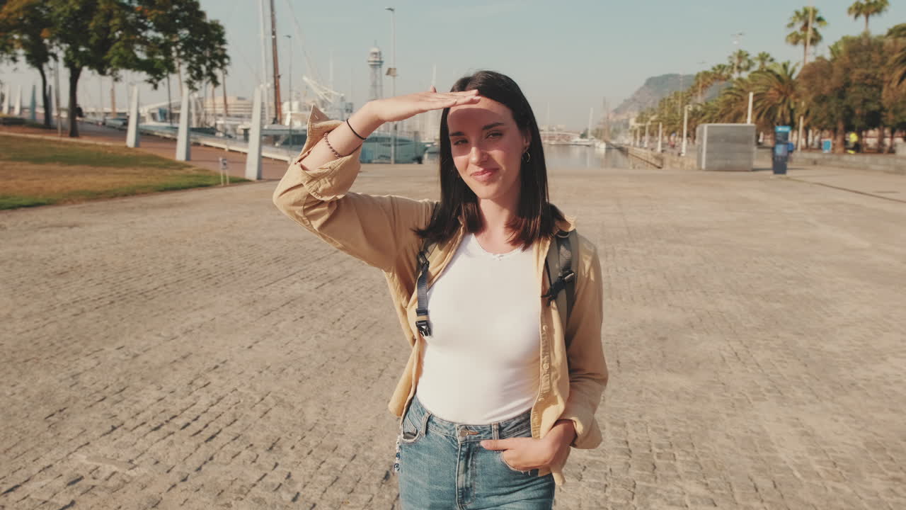 Mujer joven tapándose los ojos del sol en un puerto deportivo
