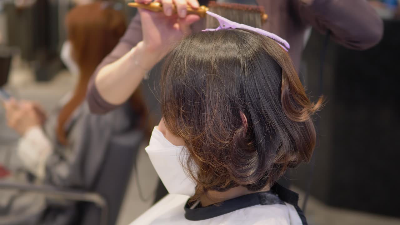 고객을 위해 물결 모양의 헤어스타일을 만들기 위해 헤어드라이어를 사용하는 헤어스타일리스트, 클로즈업