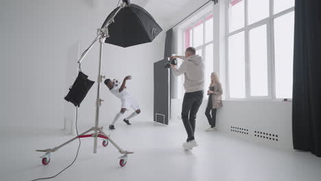 afro-american footballer is playing with ball and posing for photographer during shooting for magazine