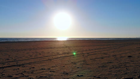 Cool,-low-aerial-4k-drone-fly-by-empty-volleyball-courts-to-beautiful-ocean-sunset-at-Huntington-Beach,-Southern-California