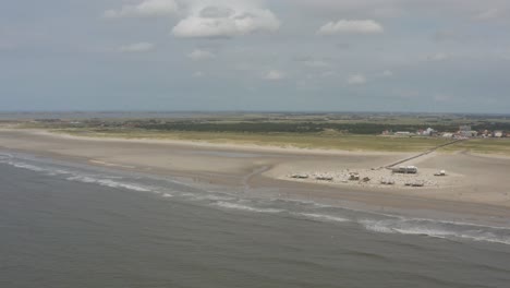 cinematic drone - aerial panorama circling shot of the sandy beach with tourists and people in st. peter ording at the north sea, schleswig holstein, germany, 30p