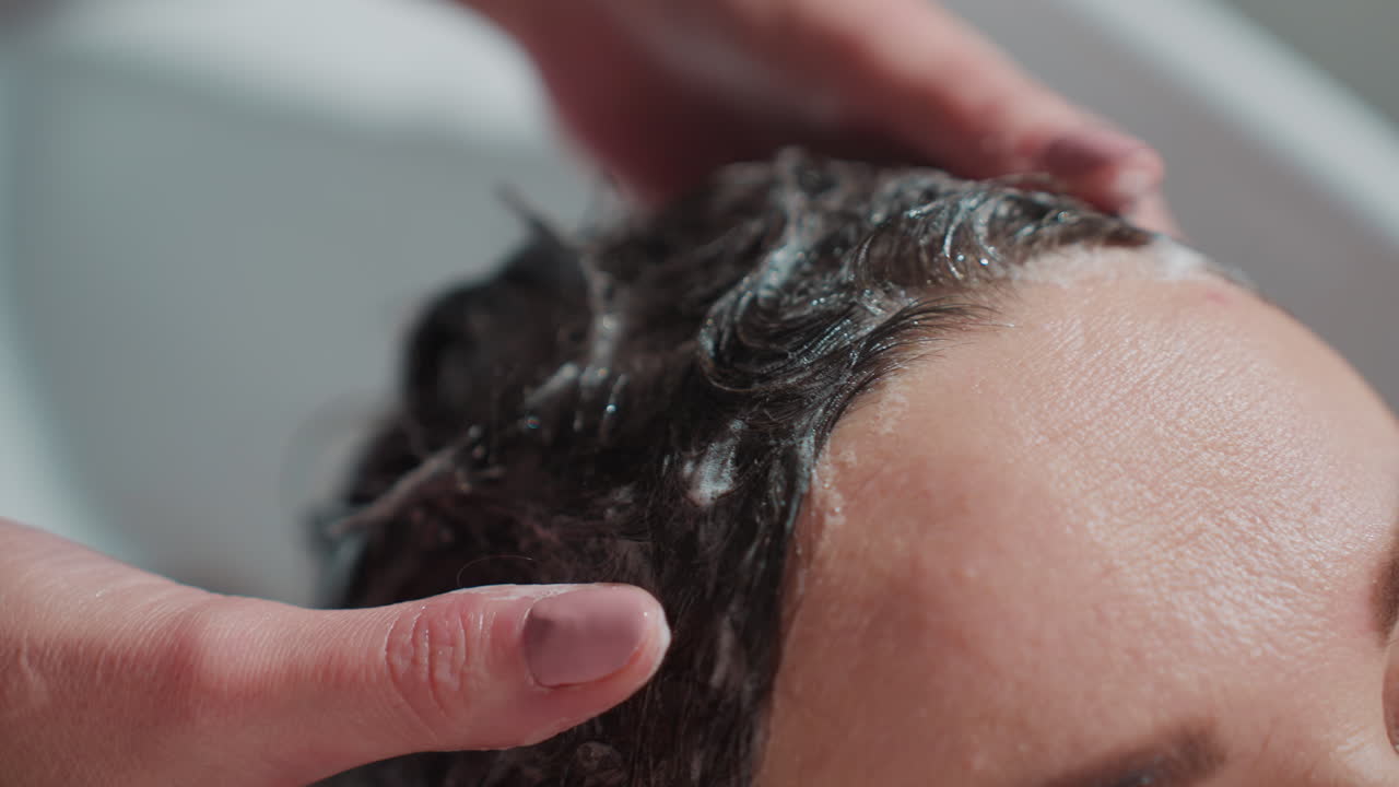 Una cliente si rilassa durante un lavaggio professionale dei capelli; una donna si gode un trattamento con shampoo rilassante in un salone di bellezza; una cliente riceve un massaggio rilassante del cuoio capelluto mentre i suoi capelli vengono lavati in modo professionale